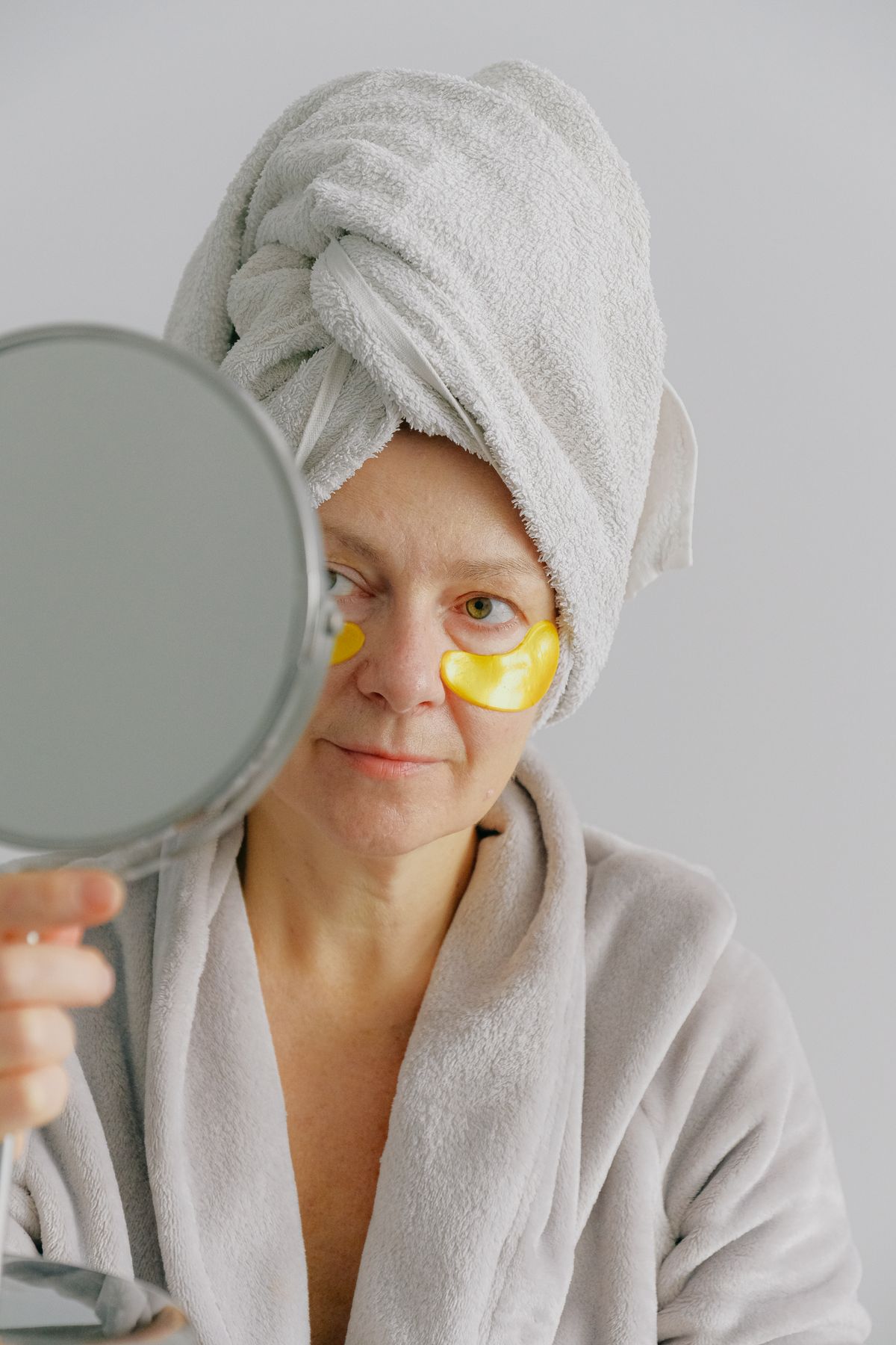 A woman examining her skin in a hand mirror