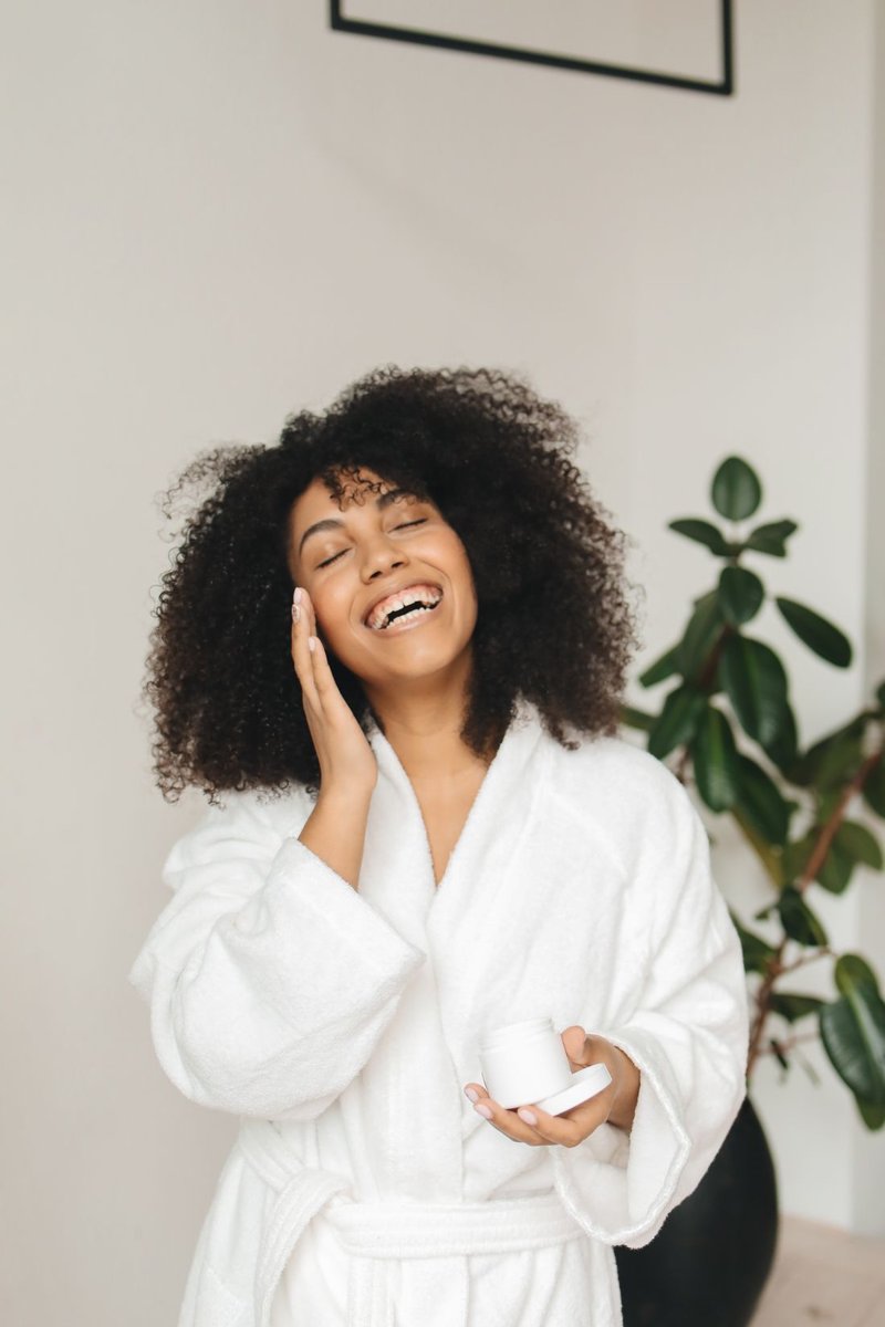 A smiling woman enjoying her skincare routine