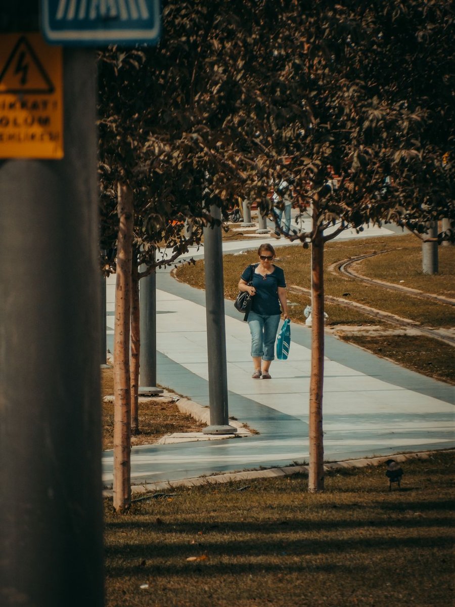 A woman walking along a tree-lined path